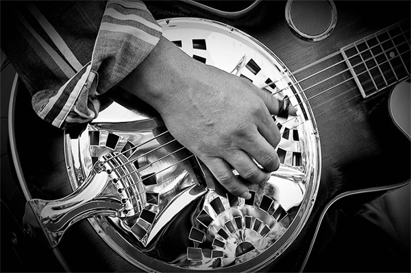 a man playing a resonator guitar - best resonator guitars