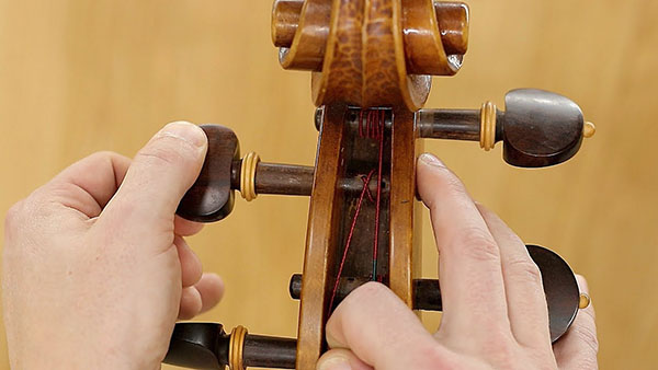 placing the strings on cello instrument