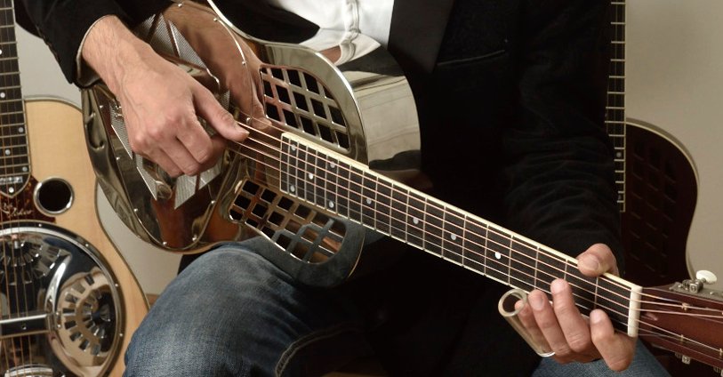 a guy playing on a beautiful resonator guitar